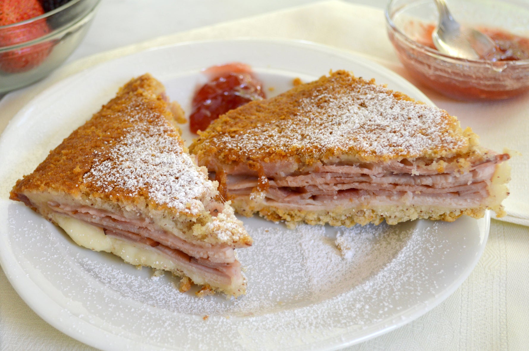 Gluten-free Monte Cristo sandwich cut diagonally with melted Swiss and powdered sugar