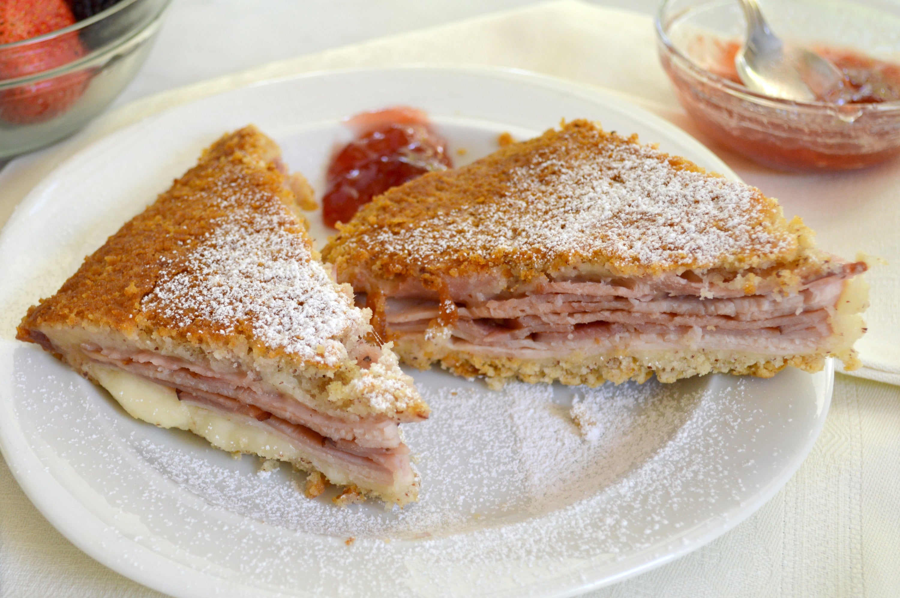 Gluten-free Monte Cristo sandwich cut diagonally with melted Swiss and powdered sugar