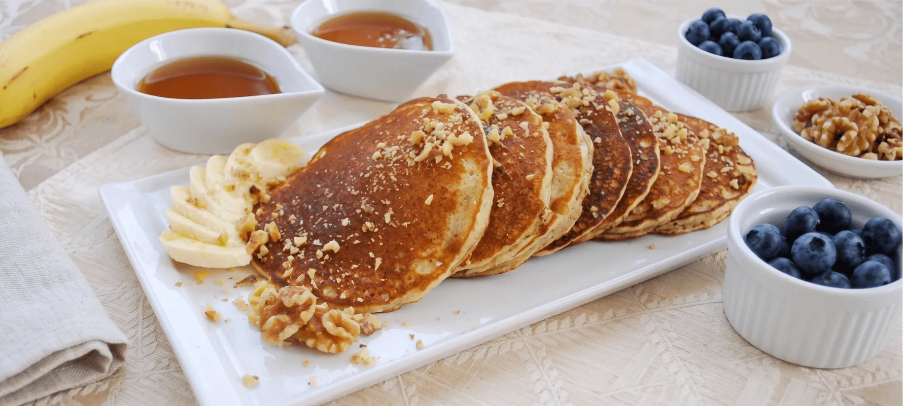 Stack of gluten-free banana pancakes with syrup and sliced banana