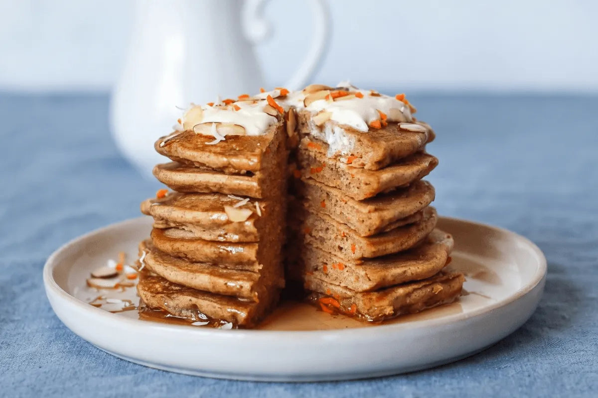 Stack of gluten-free carrot cake pancakes with cream cheese glaze pouring over