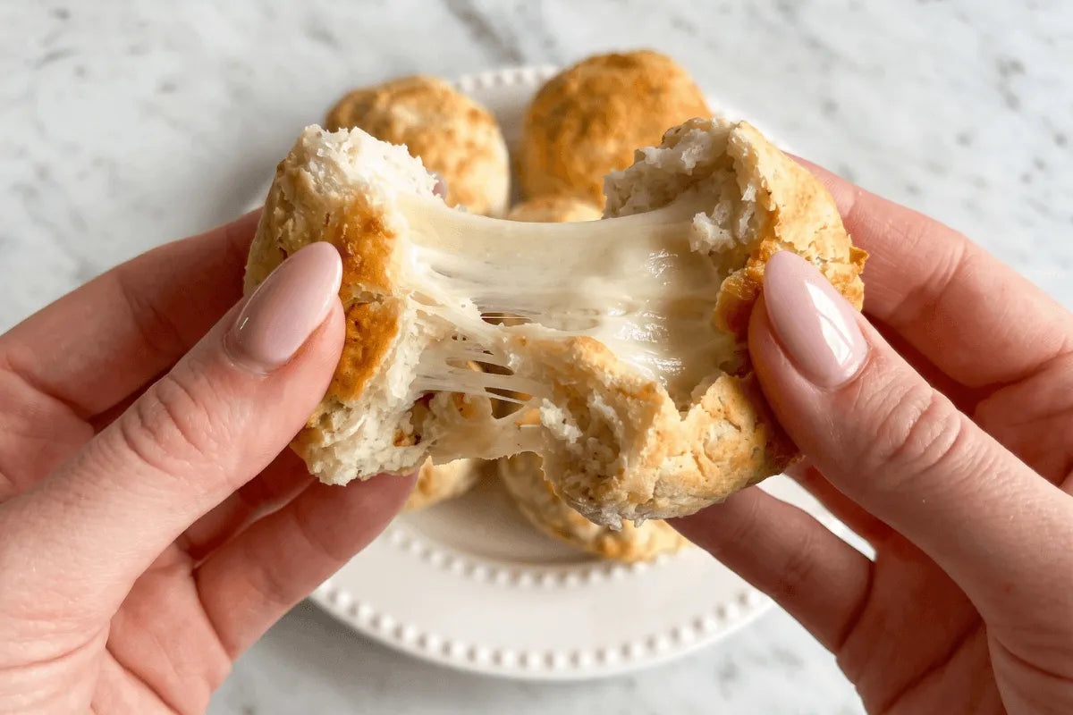 Gluten-free pizza bite pulled apart with melted mozzarella stretching between the halves