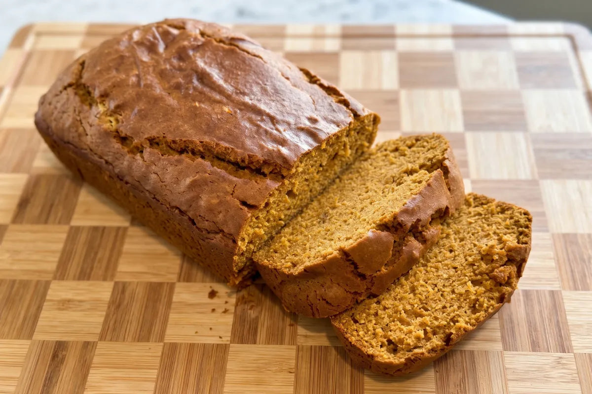 Sliced gluten-free pumpkin bread on a wooden board showing a soft, moist crumb