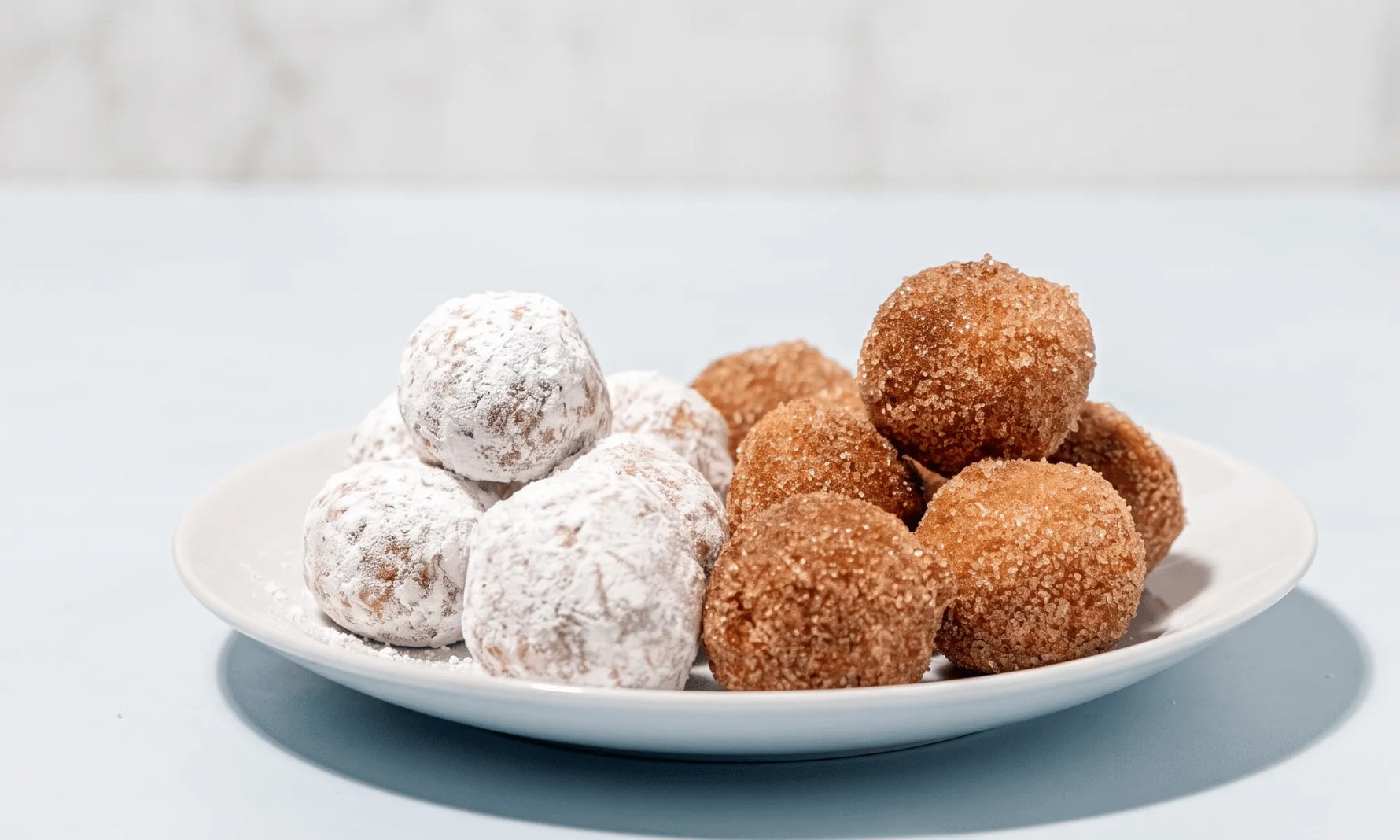 Gluten-free donut holes rolled in cinnamon sugar, piled on a plate