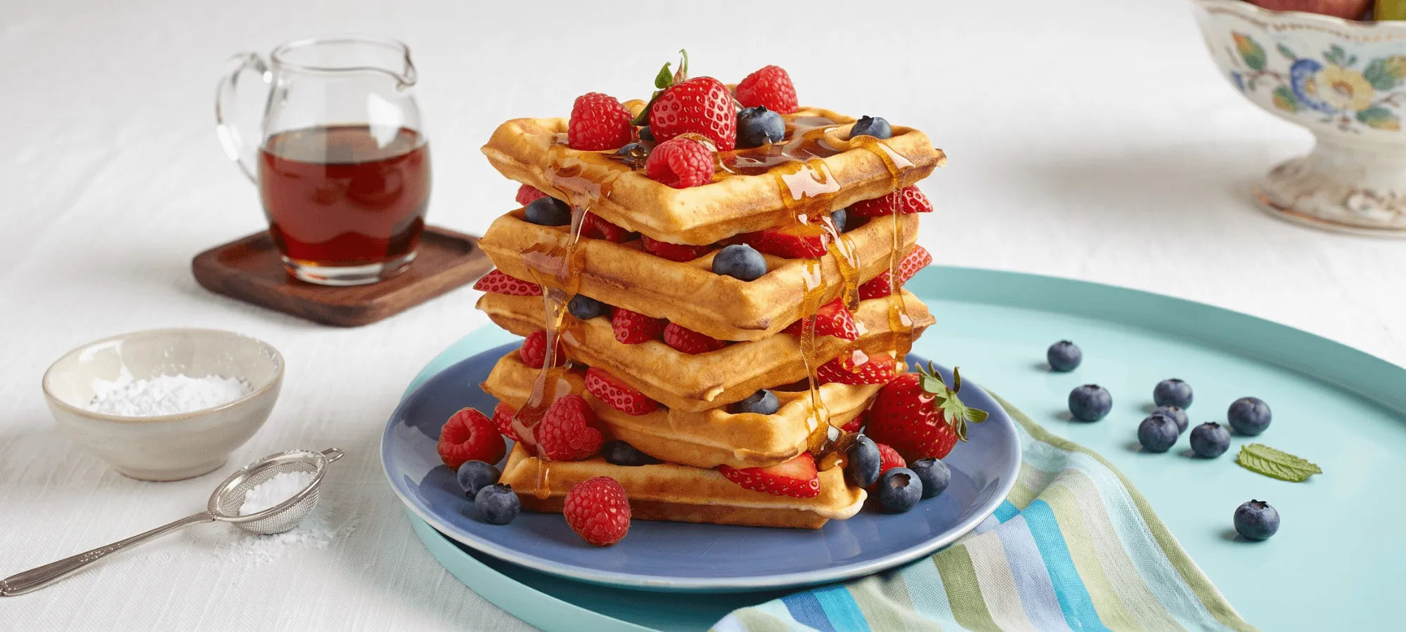 Stack of crisp gluten-free waffles with butter and syrup pouring over