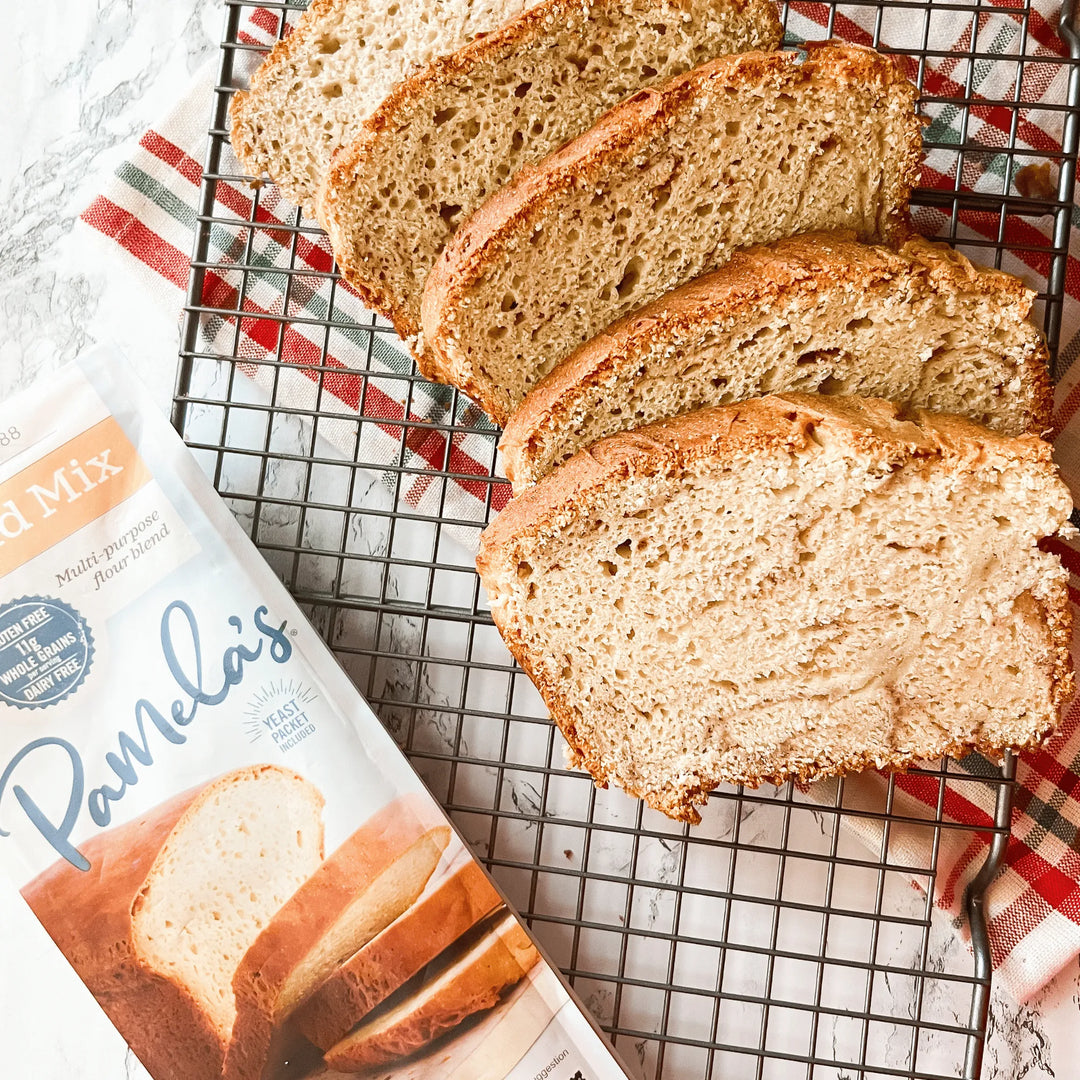 Sliced loaf of bread on a cooling rack with Pamela's Bread Mix packaging.
