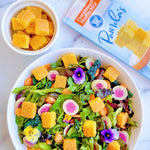 Colorful salad with cornbread muffin bits and a box of Pamela's Cornbread Muffin Mix on a white background.