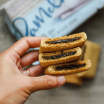 Hand holding a stack of cookies with dark filling, blurred background