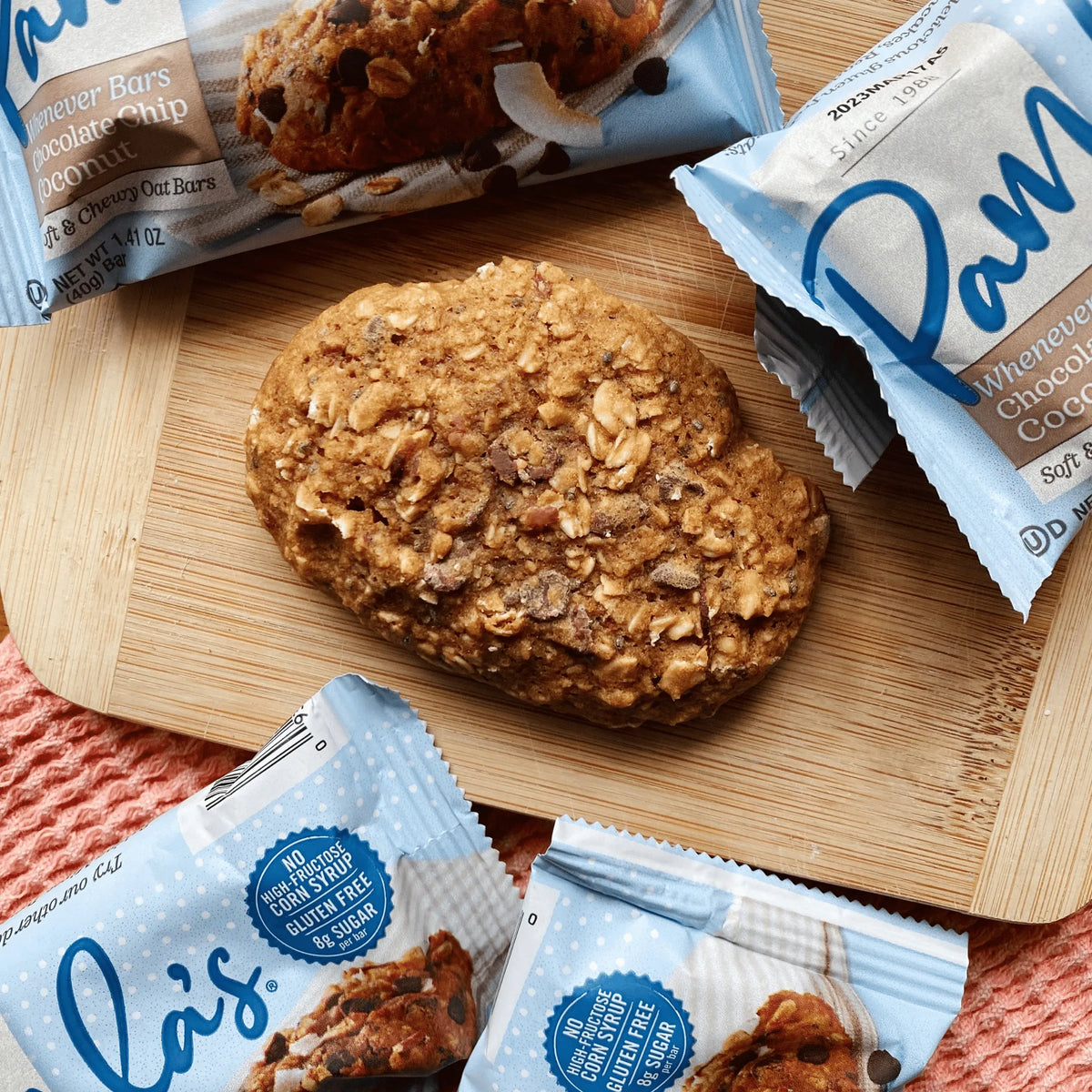Cookie on a wooden board with Pamela's chocolate chip cookie packages around it.