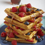Stack of waffles with berries and syrup on a blue plate